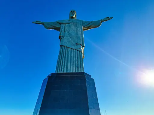 Cristo Redentor, die berühmte Statue in Rio de Janeiro, breitet seine Arme unter strahlend blauem Himmel aus.