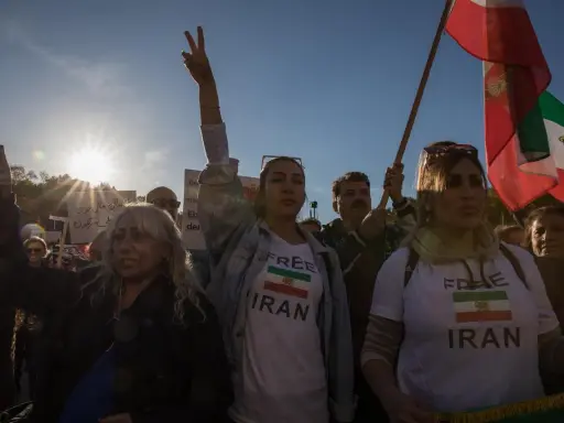 Menschen demonstrieren für ein free Iran. Eine Frau hält ein Schild mit der Aufschrift "Free Iran" und der iranischen Flagge.