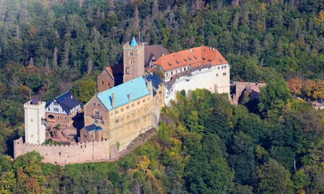 Die Wartburg, Ort von Luthers Thesen, thront auf einem bewaldeten Berg.