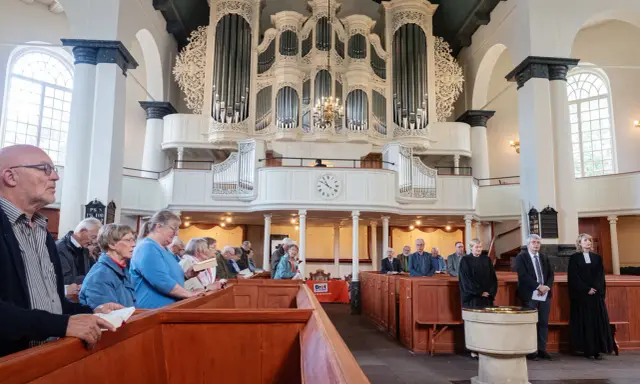 Gemeinde in einer reformierten Kirche mit imposanter Orgel.