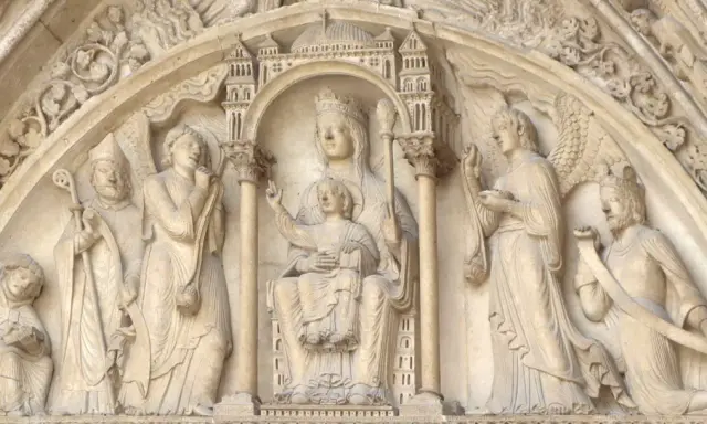 Steinrelief mit Maria und Kind, flankiert von Heiligen und Engeln. Die Bedeutung von Saint Germain wird hier durch die Darstellung von Heiligen und biblischen Szenen unterstrichen.