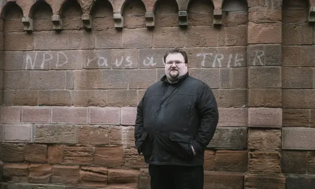 Safet Babic steht vor einer Mauer mit Graffiti.