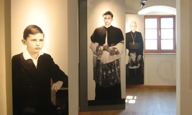 Ausstellung zeigt Maria Ratzinger in verschiedenen Lebensphasen: als Kind, junger Mann und als Geistlicher mit Kind.
