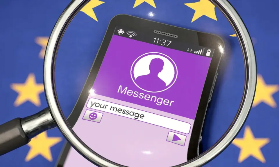 Lupe über Smartphone mit Messenger-App vor EU-Flagge. Diskussionen über Chatkontrolle EU.