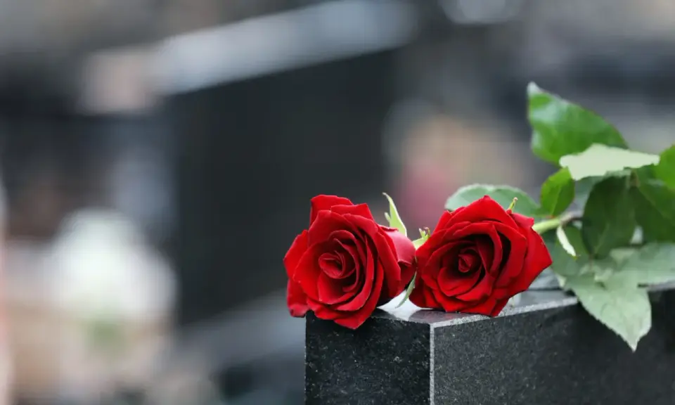 Zwei rote Rosen auf einem Grabstein, ein Symbol der Erinnerung 40 Tage nach dem Tod im katholischen Glauben.
