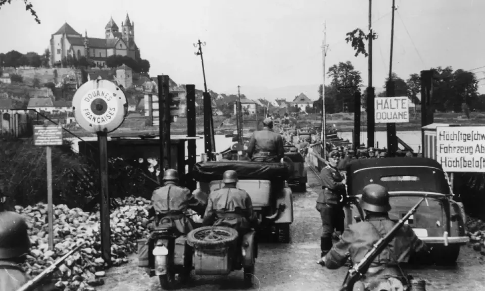 Soldaten kontrollieren Fahrzeuge an einer Grenze. Ein Schild zeigt "Douanes Françaises". Ein Blick auf die elsass geschichte.