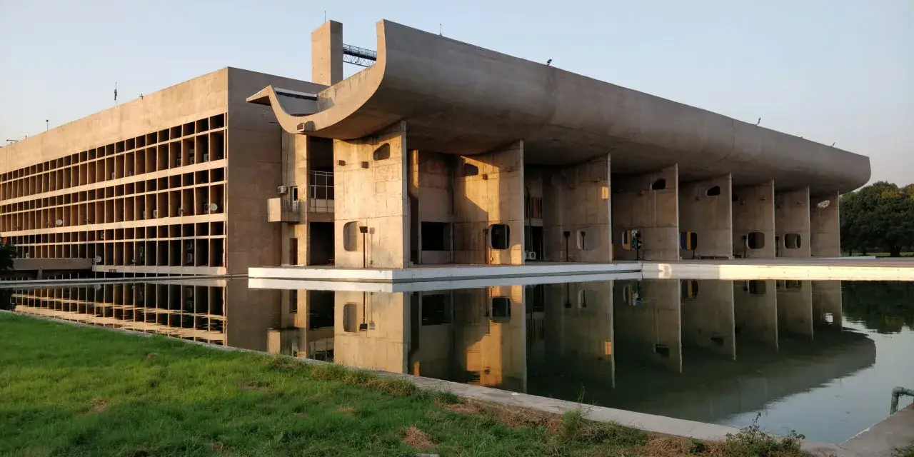 Le Corbusiers Kapitol-Gebäude in Chandigarh, Indien, spiegelt sich in einem ruhigen Wasserbecken.