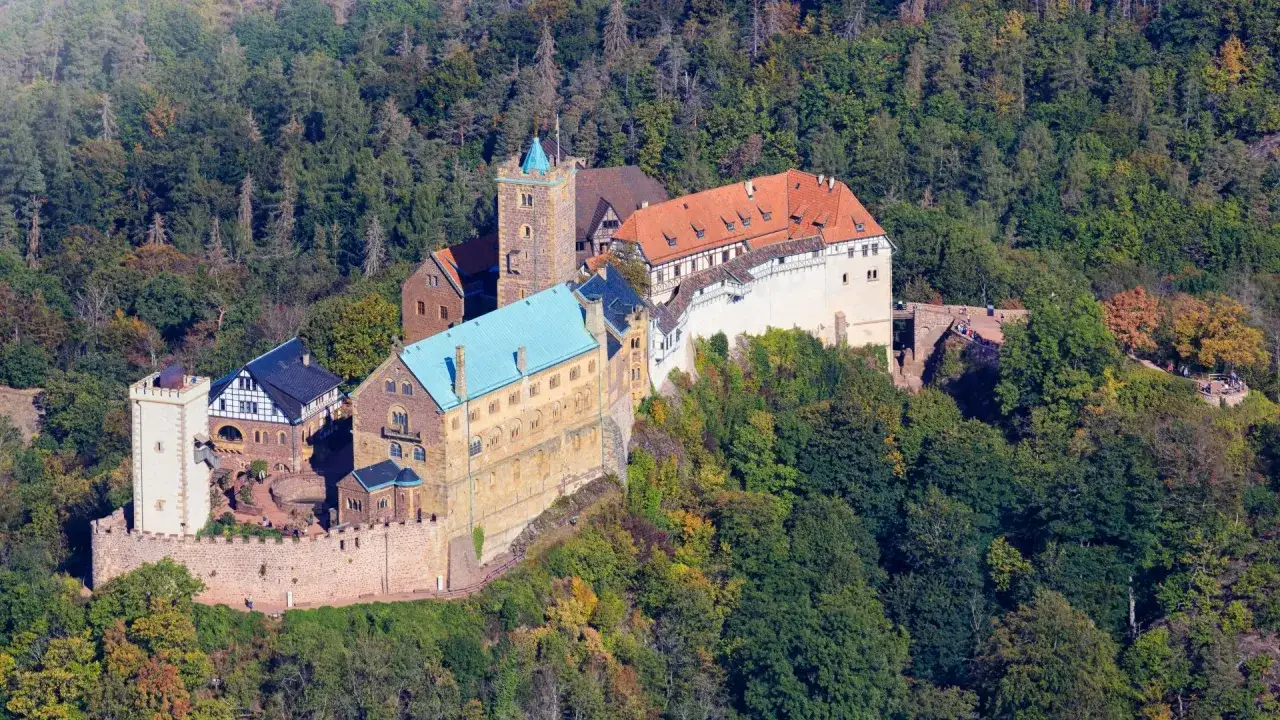Die Wartburg, wo Luther die Thesen übersetzte, thront auf einem bewaldeten Berg.
