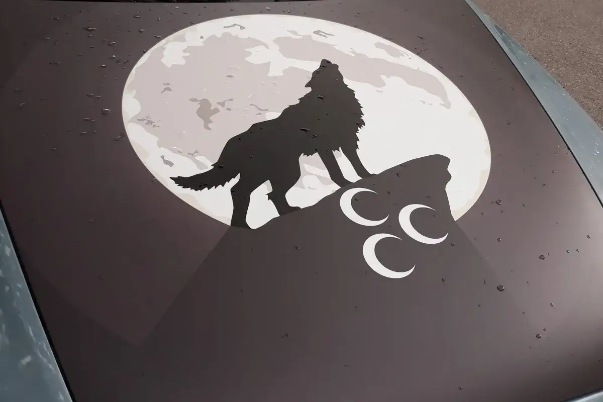 Ein grauer Wolf heult den Mond an, der auf einem Felsen steht. Drei weiße Halbmonde sind unter ihm.