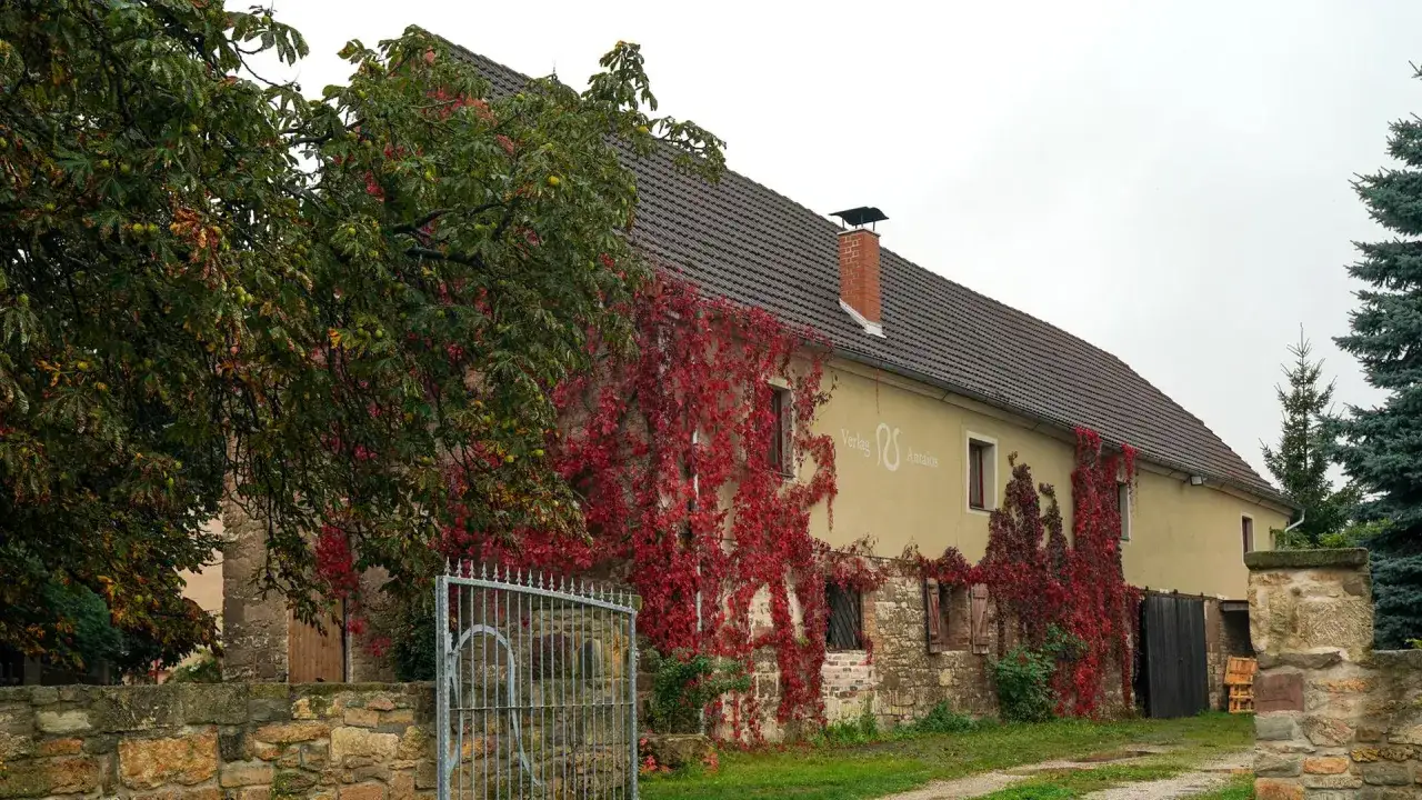 Herbstliche Weinreben ranken sich um das Gebäude des Antaios Verlags.