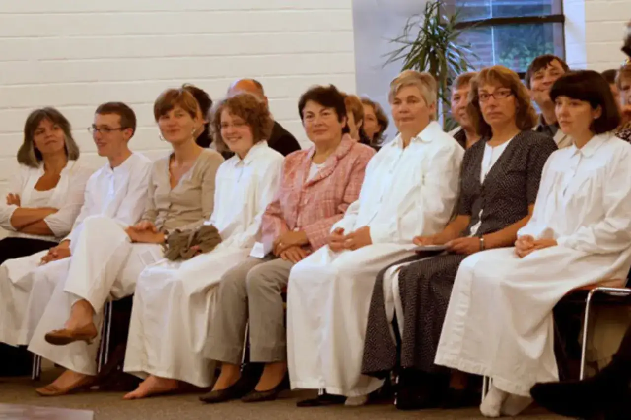 Menschen in weißen Gewändern sitzen nebeneinander. Sie sind Teil einer Gemeinschaft, die sich als Baptisten versteht.