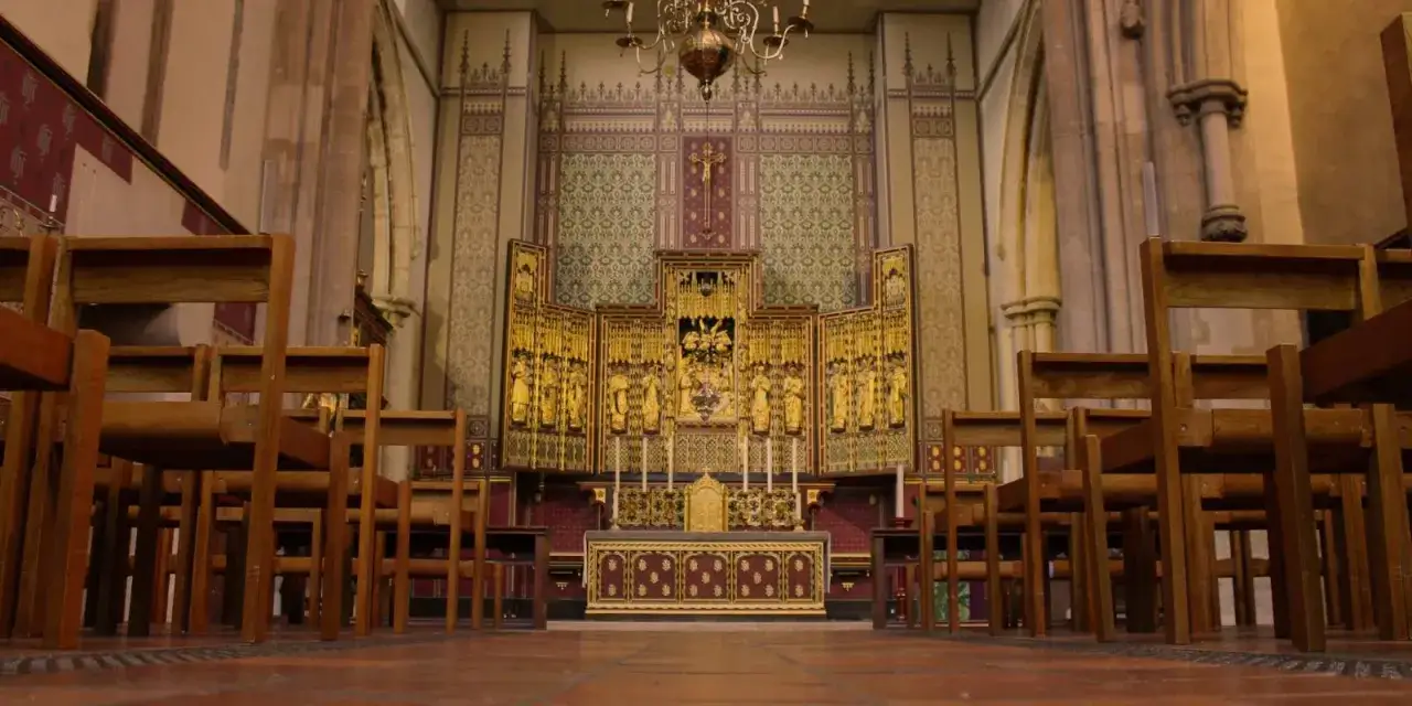 Holzstühle vor dem goldenen Altar einer Kirche von England.