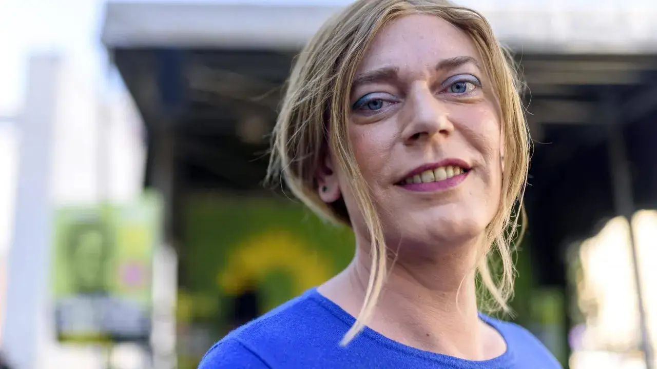 Porträt von Markus Ganserer, der in die Kamera lächelt. Er trägt ein blaues Oberteil und hat blonde Haare.