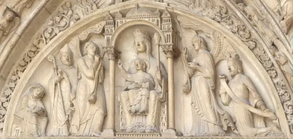 Steinrelief mit Maria und Kind, flankiert von Heiligen und Engeln. Die Bedeutung von Saint Germain wird hier durch die Darstellung von Heiligen und biblischen Szenen unterstrichen.